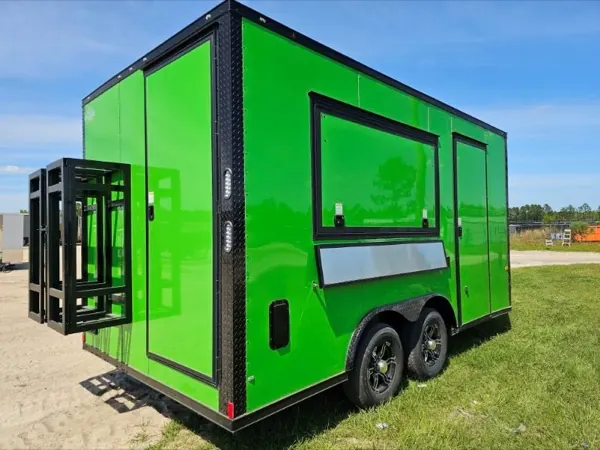 Green concession trailer with a serving window, side door, and a black rack mounted on the front