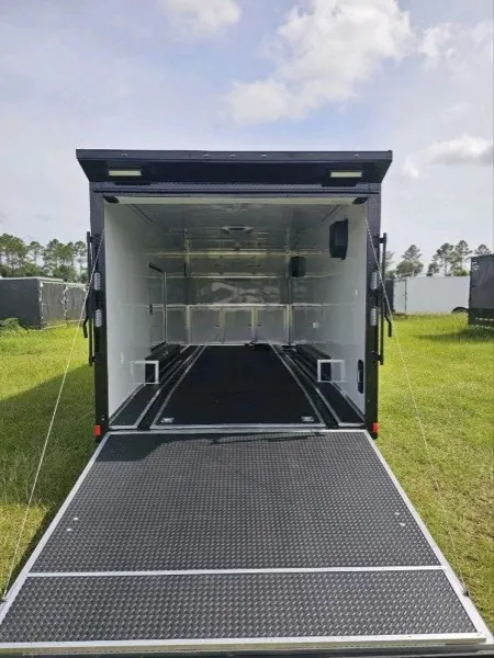 Interior of an enclosed trailer with the rear ramp down, showing finished white walls and a black floor