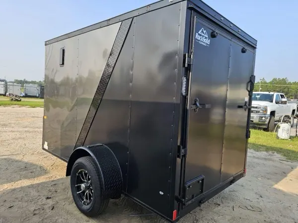 Charcoal single axle cargo trailer with a side door and black wheels, rear three-quarter view