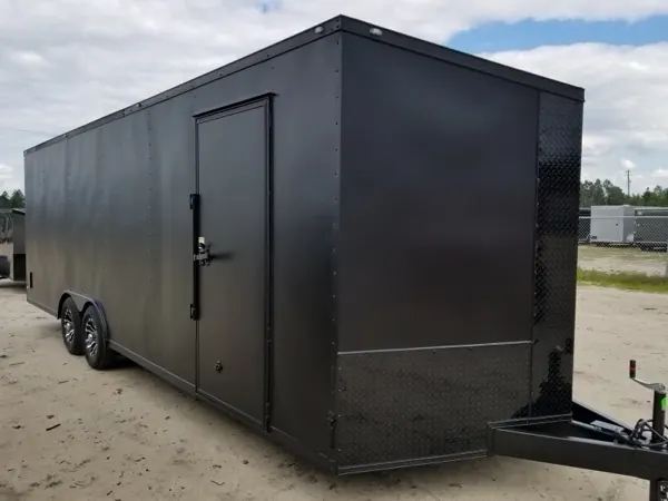 Matte charcoal tandem axle cargo trailer with blacked out trim and a side door, side view
