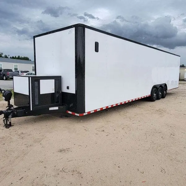 White tri-axle cargo trailer with a front storage box and reflective tape along the side